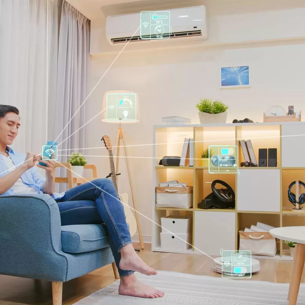 A man sitting in his apartment and controlling all of his smart devices from his phone.